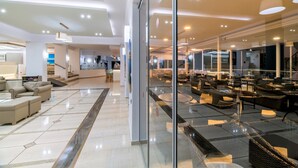 A spacious lobby with modern furniture, a glass partition, and a well-lit ceiling.