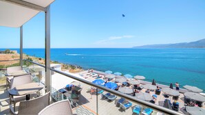 A balcony with outdoor seating and a view of the sea.