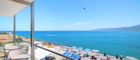 A balcony with outdoor seating overlooking a coastal view.