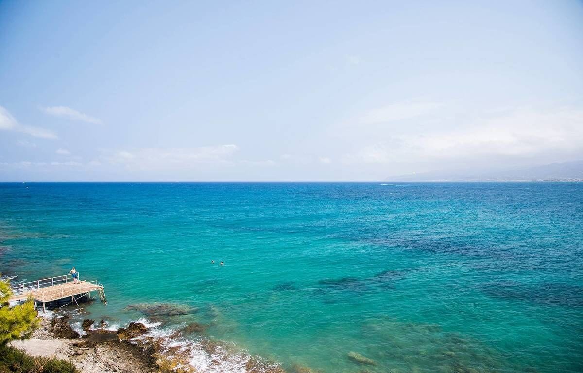 A coastal view with a pier extending into turquoise waters.