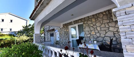 A stone building with a balcony, a window, and a door.