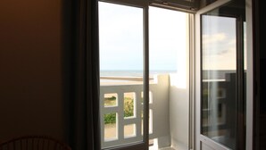 Una stanza con un'ampia porta finestra scorrevole che si apre su un balcone con vista sulla spiaggia e sull'oceano.