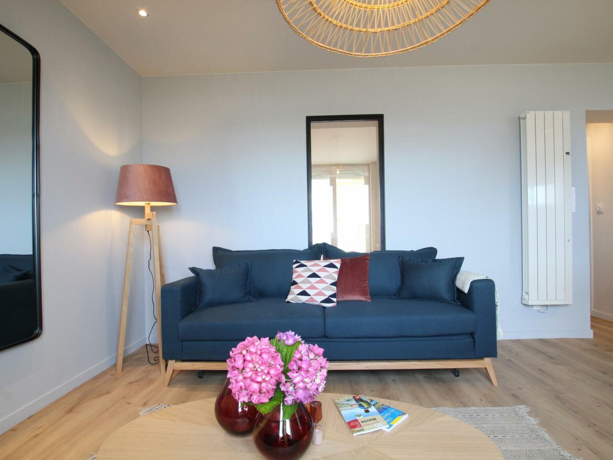 A modern living room with a blue sofa, a floor lamp, a mirror, and a radiator.