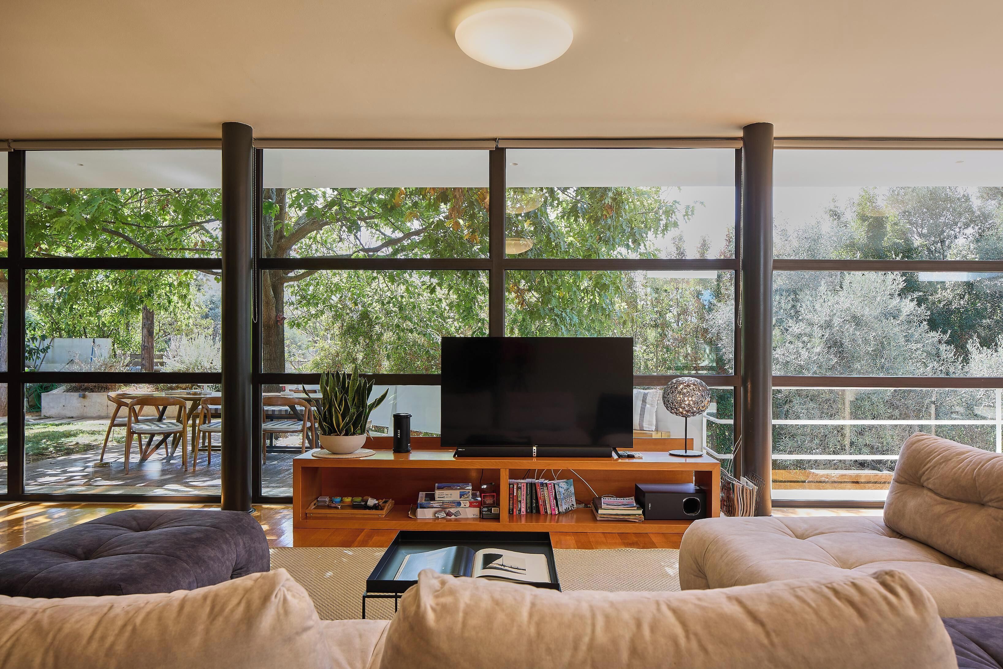 Una sala de estar moderna con un televisor grande, mueble de entretenimiento de madera y asientos cómodos.