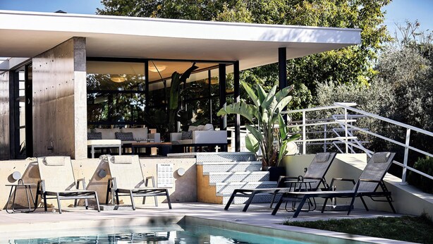 Un espace piscine extérieur moderne, doté de chaises longues et d’un coin salon abrité.