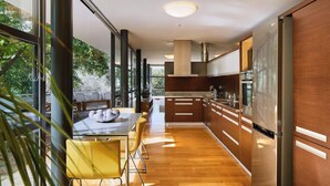 Une cuisine moderne avec des meubles en bois, des appareils en acier inoxydable et un coin repas doté de chaises jaunes.