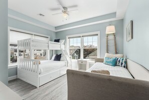 A room with bunk beds, a desk, a chair, a lamp, and a window with a view. - Beachside Abode 2B (Old Orchard Beach)