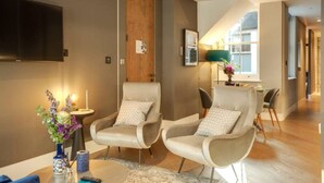 A modern living room with two armchairs, a coffee table, and a TV mounted on the wall. - Impeccable 1-bedroom Apartment in London (London)