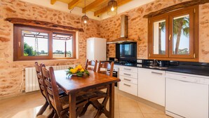 Una cocina con una mesa de madera, sillas, un refrigerador blanco, una estufa y un lavavajillas.