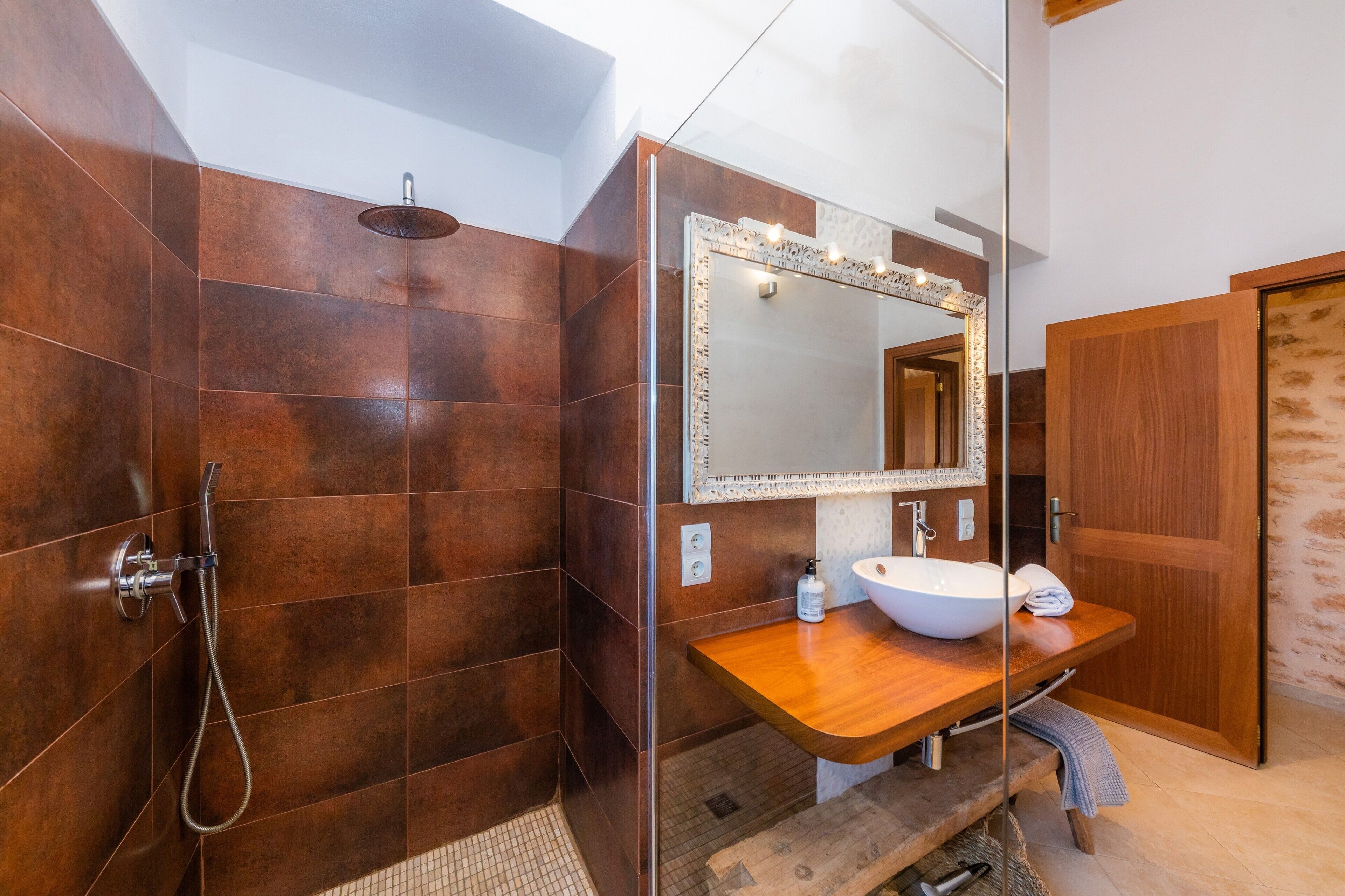 Un baño con ducha, lavamanos y espejo.