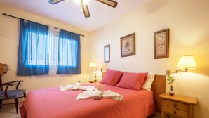 Una camera d'hotel con un letto grande, due abat-jour, un comodino, una sedia e una finestra con tende.
