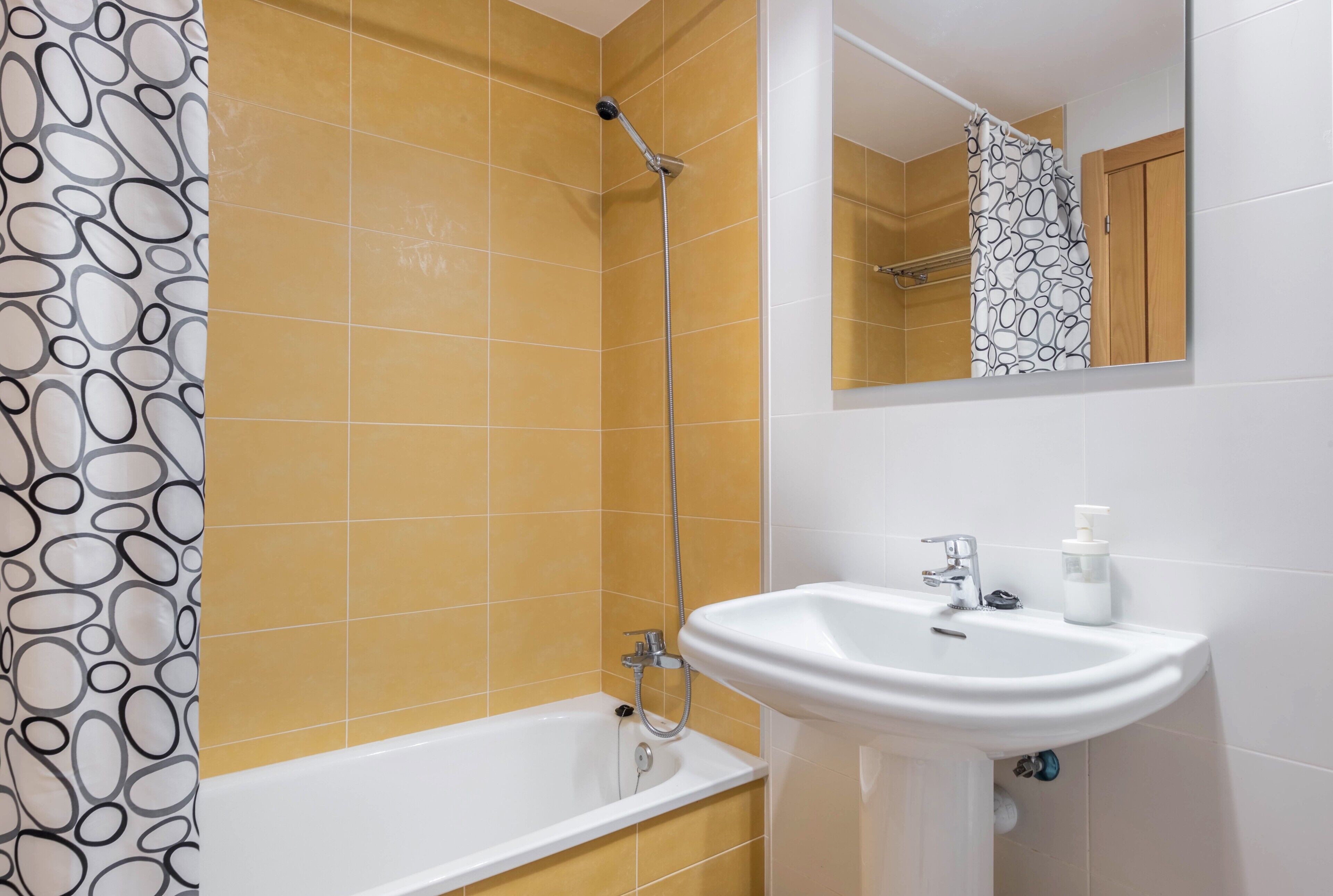 Ein Badezimmer mit einer Badewanne, einer Dusche, einem Waschbecken und einem Spiegel.
