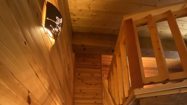 Een houten interieur met een houten trap en een lamp aan de muur.