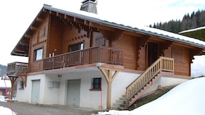 Een houten chalet met balkon, trap en garage.
