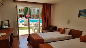 A hotel room with two beds, a desk, a television, and a sliding glass door leading to a pool area. - Sun City Hotel (Sunny Beach)