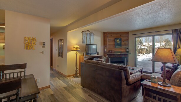 Una sala de estar acogedora con chimenea, televisor y comedor con mesa y sillas de madera.