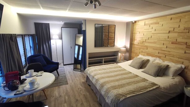 A hotel room with a bed, a desk with a chair, a mirror, a wardrobe, and a window with curtains. - Au St Martin 2 (Cholet)