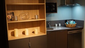 A kitchen with wooden shelves, a sink, and a basket of kitchen utensils. - Au St Martin 2 (Cholet)
