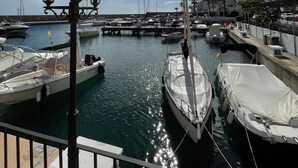 Un port de plaisance avec des bateaux amarrés, un ciel dégagé et un soleil qui brille à travers les nuages.