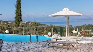 Ein Poolbereich mit Liegestühlen, einem Rettungsboje und Blick aufs Meer.