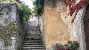 Uma escadaria de pedra estreita que sobe até um edifício, com uma bicicleta vermelha encostada na parede.