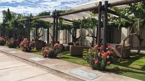 A covered outdoor seating area with pergolas, potted plants, and a paved walkway. - Casa Agostino - Luxury wine resort (Fray Luis Beltrán)