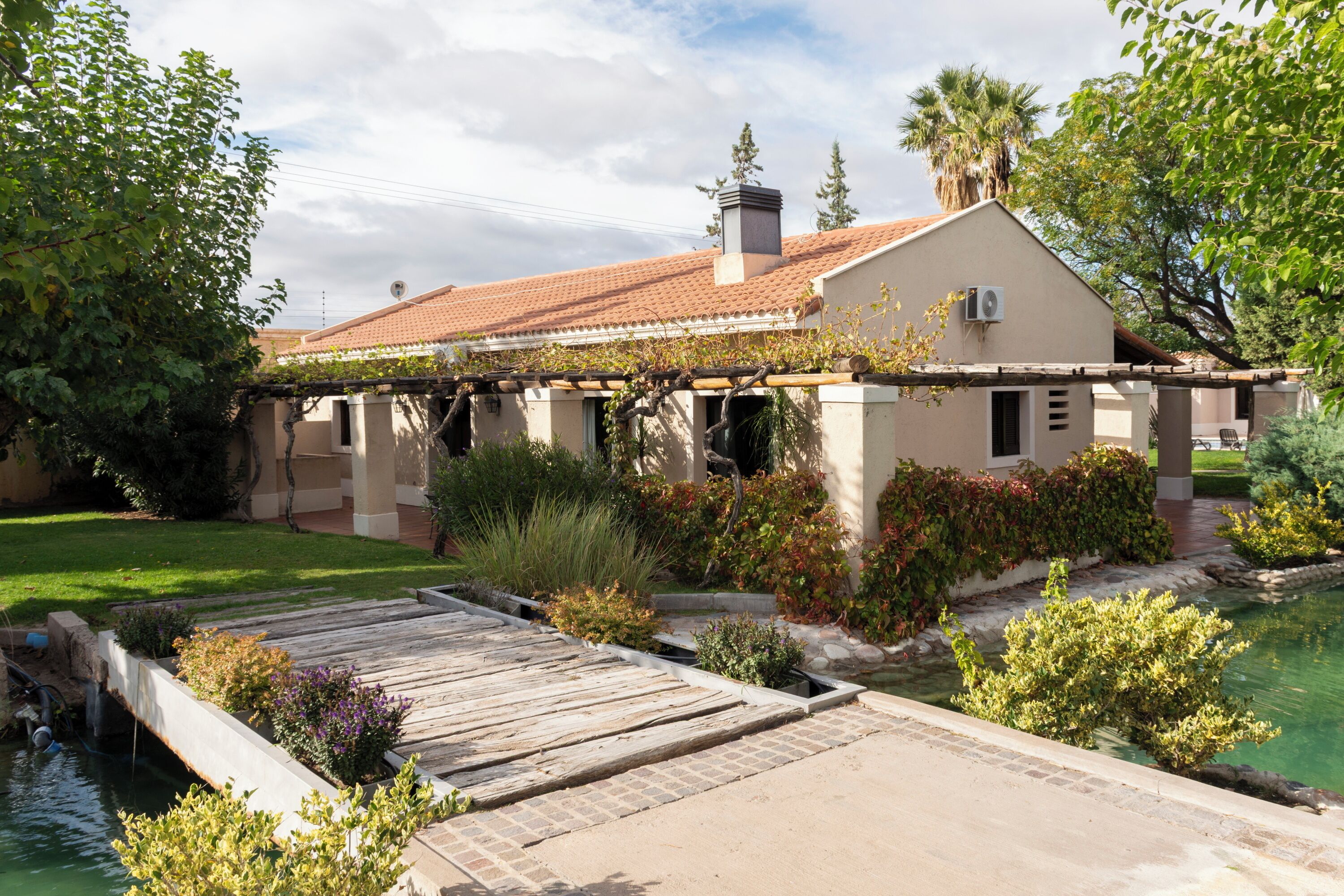 A house with a garden, a swimming pool, and a pergola.