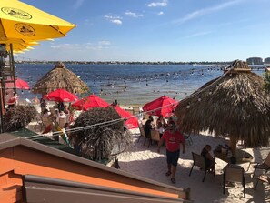 A beachside restaurant with outdoor seating, thatched umbrellas, and a view of the sea. - Luxury Paradise Suite (Cape Coral)