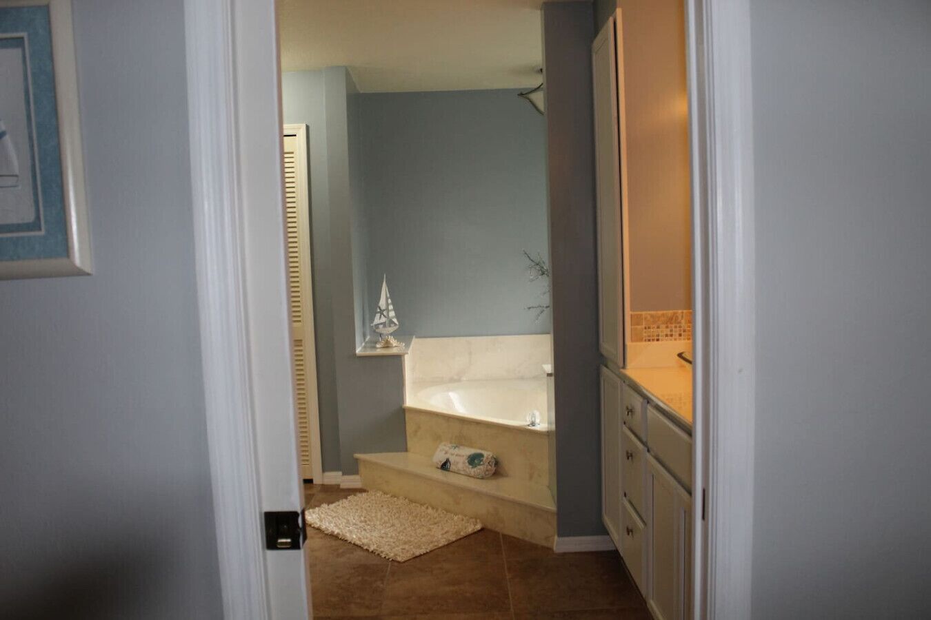 A bathroom with a bathtub, a small shelf with a decorative item, and a towel rack.