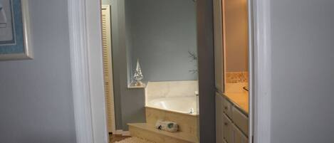 A bathroom with a bathtub, a small shelf with a decorative item, and a towel rack.