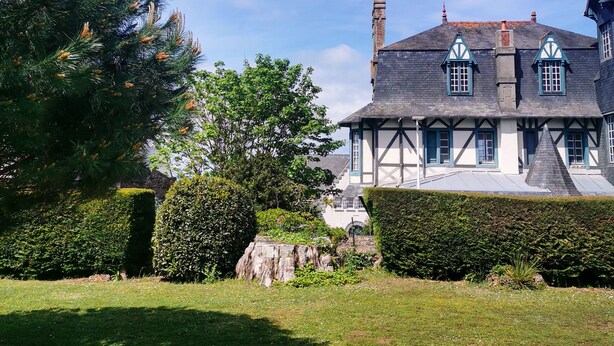 Ein traditionelles Haus im Tudor-Stil mit einem steilen Satteldach, Gauben und einem Schornstein.