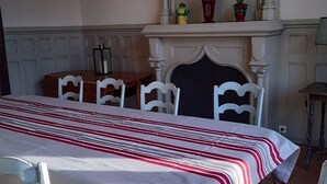 Ein Essbereich mit einem Tisch für vier Personen, weißen Stühlen, einem Kamin mit Dekoration und einem weißen Sims.