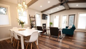 A spacious living area with a dining table, chairs, a fireplace, and a teal sofa.