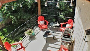 A covered outdoor patio with red chairs, a small table, and a fire pit.