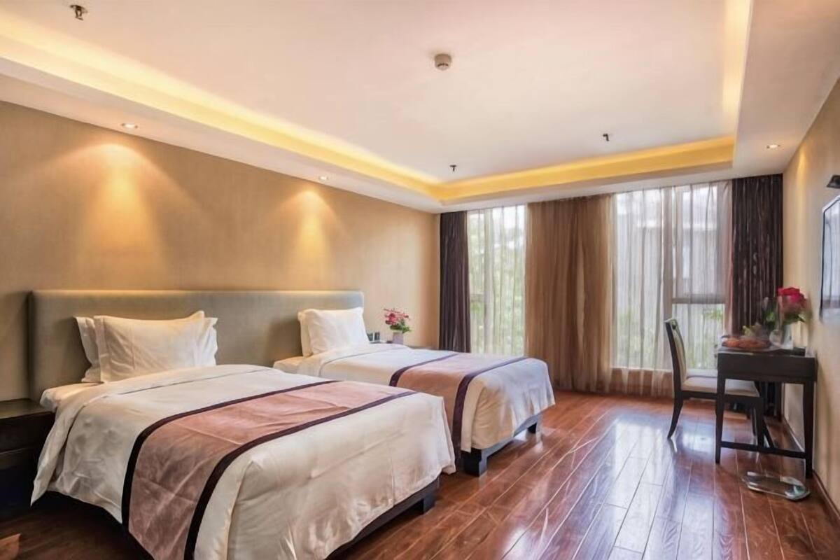A hotel room with two beds, a small table, and a chair.