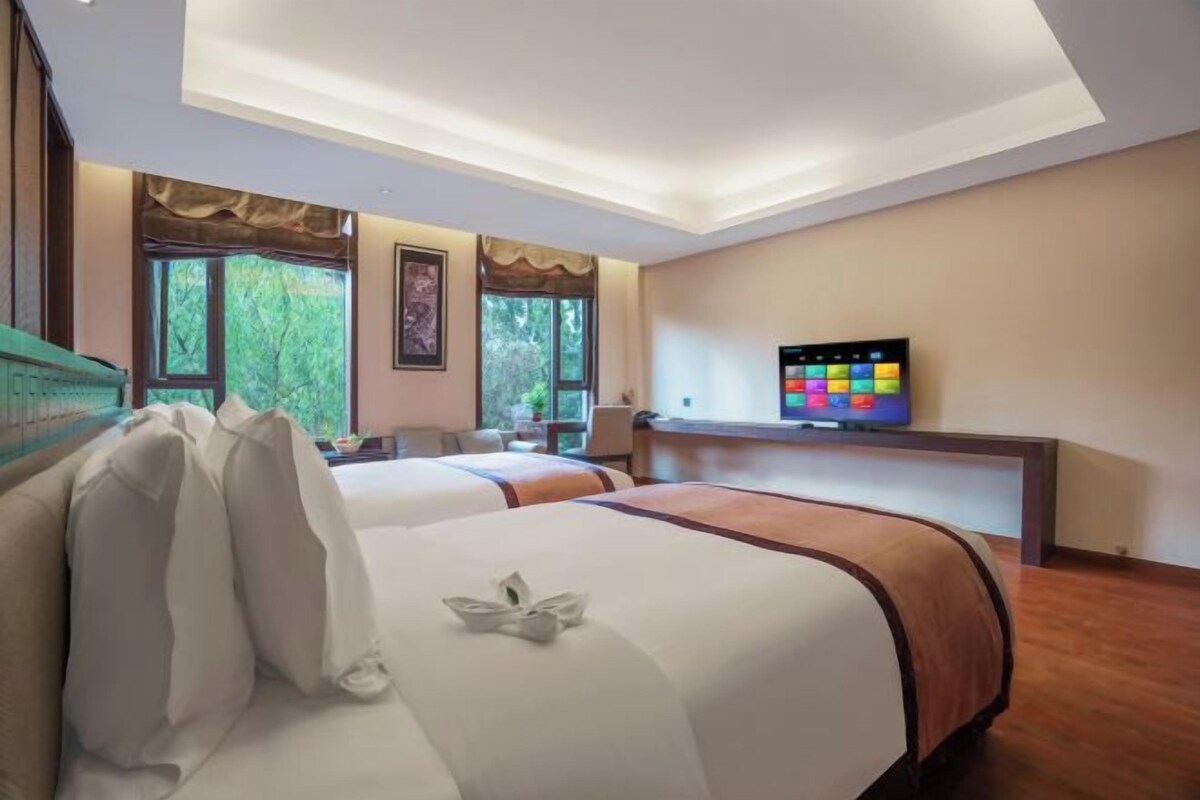 Una camera d'albergo con due letti, una televisione e una scrivania.