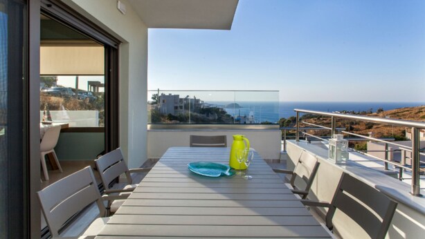 Ein Balkon mit Tisch, Stühlen und Blick aufs Meer.