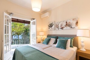 A bedroom with a bed, a nightstand, a lamp, and a window with an open door.