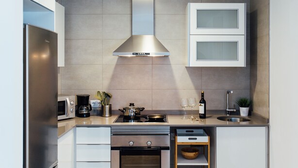 Een moderne keuken met roestvrijstalen apparatuur, een inbouwoven, een afzuigkap en een dubbele spoelbak.