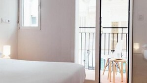 Een hotelkamer met een bed, een raam en een balkon met een stoel en een tafel.