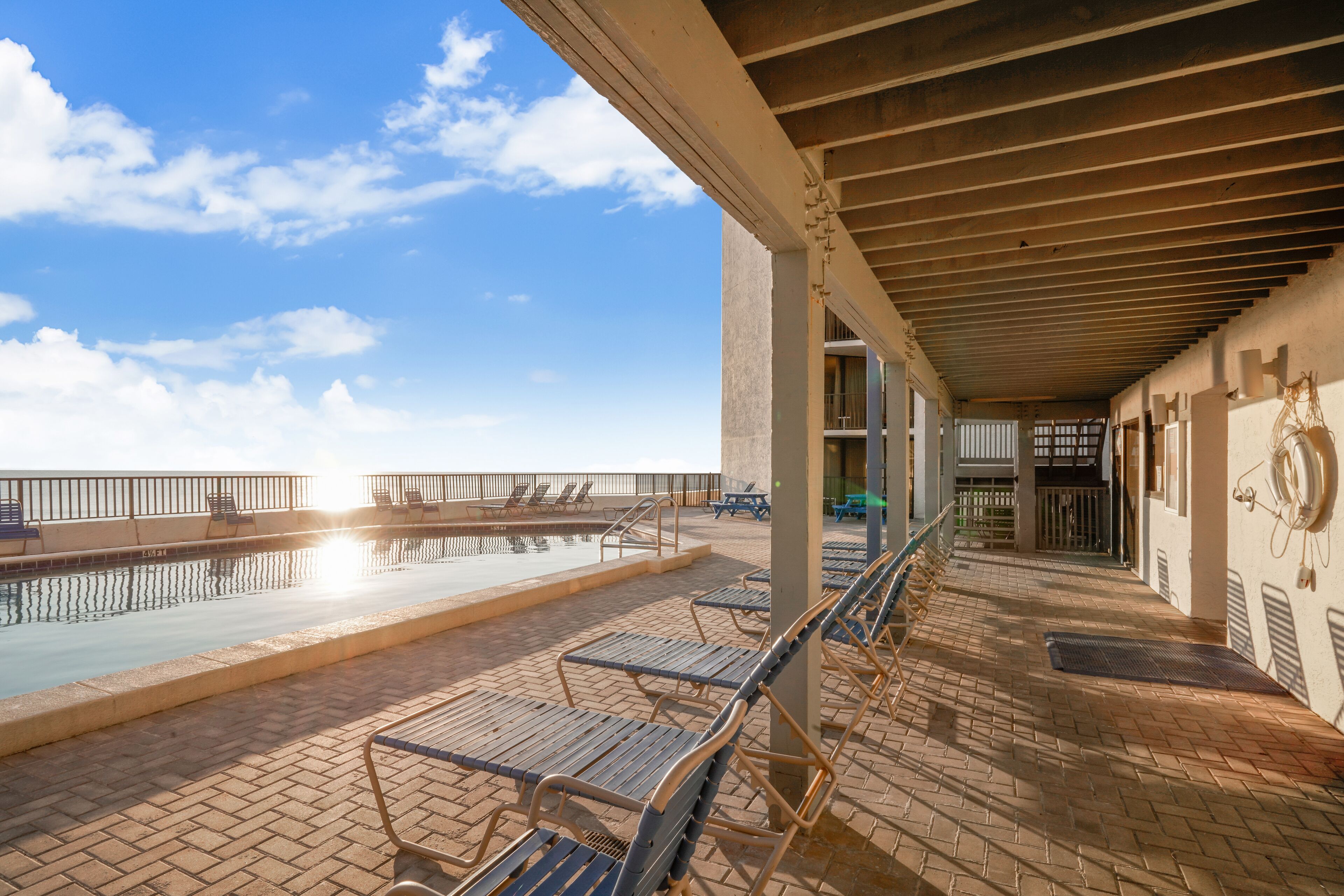 Un espace aménagé au bord de la piscine, avec des chaises longues et une allée couverte.