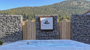 A hot tub in an outdoor setting with a wooden fence and a sign that reads "Refuges des Truches." - Le Familial 4* - SPA & SAUNA - 6 people (Rochesson)