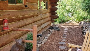 A rustic wooden cabin with a deck, a bear statue, and a cozy seating area. - Beautiful Log Cabin w/ Beachfront & Stunning Lake Views in Coeur d'Alene Idaho. (Harrison)