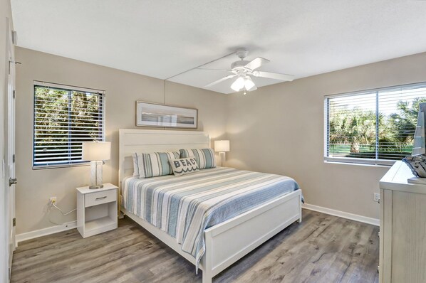 A bedroom with a bed, bedside tables, a ceiling fan, and windows with blinds. - Pet-Friendly Villa w/ Views of the 9th Fairway at Atlantic Dunes! (Hilton Head Island)