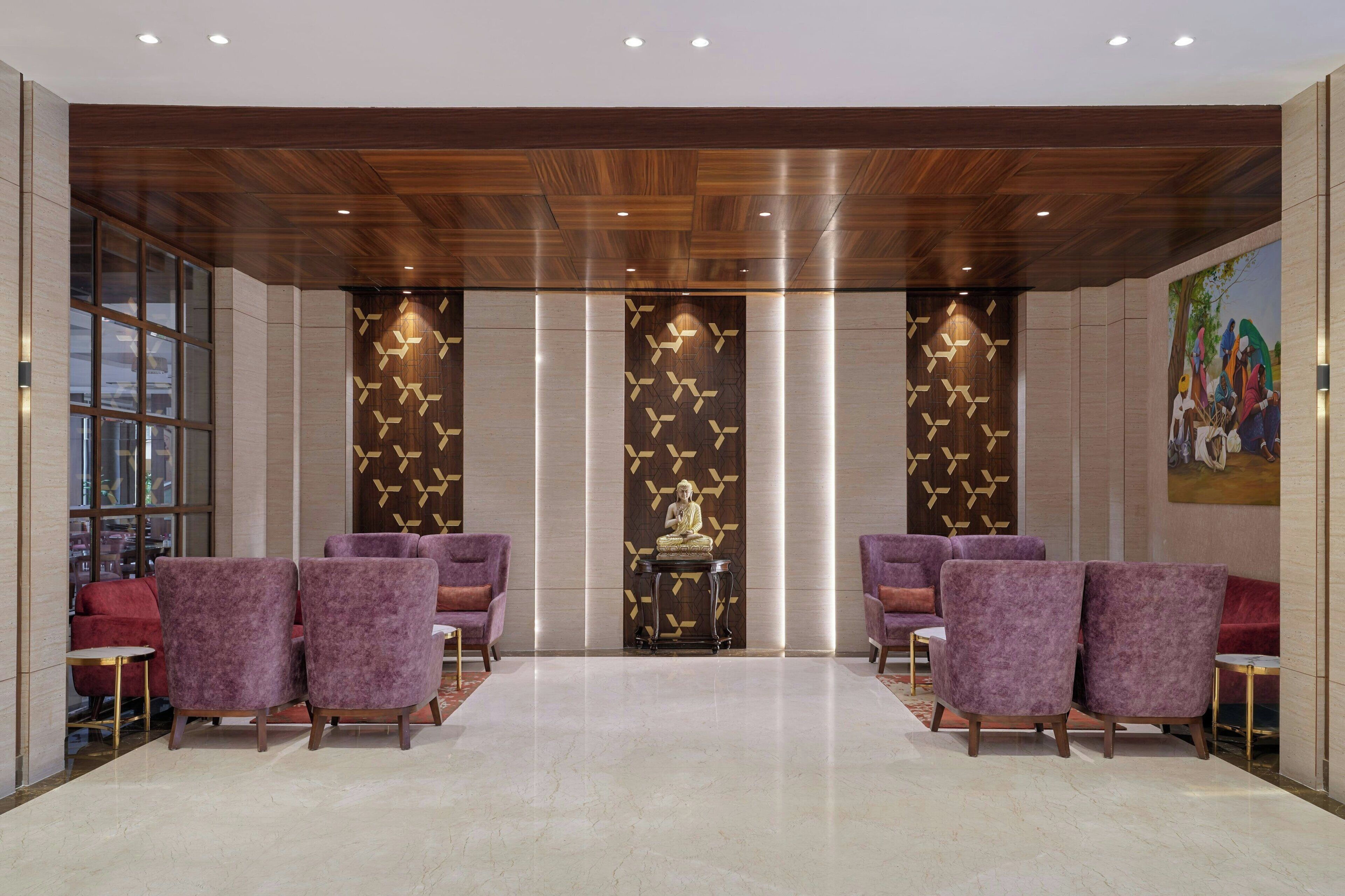 A lobby with purple seating, a statue, and a wooden ceiling.