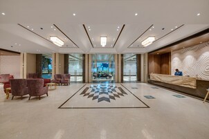 A spacious lobby with a checkered floor, seating area, and a reception desk.
