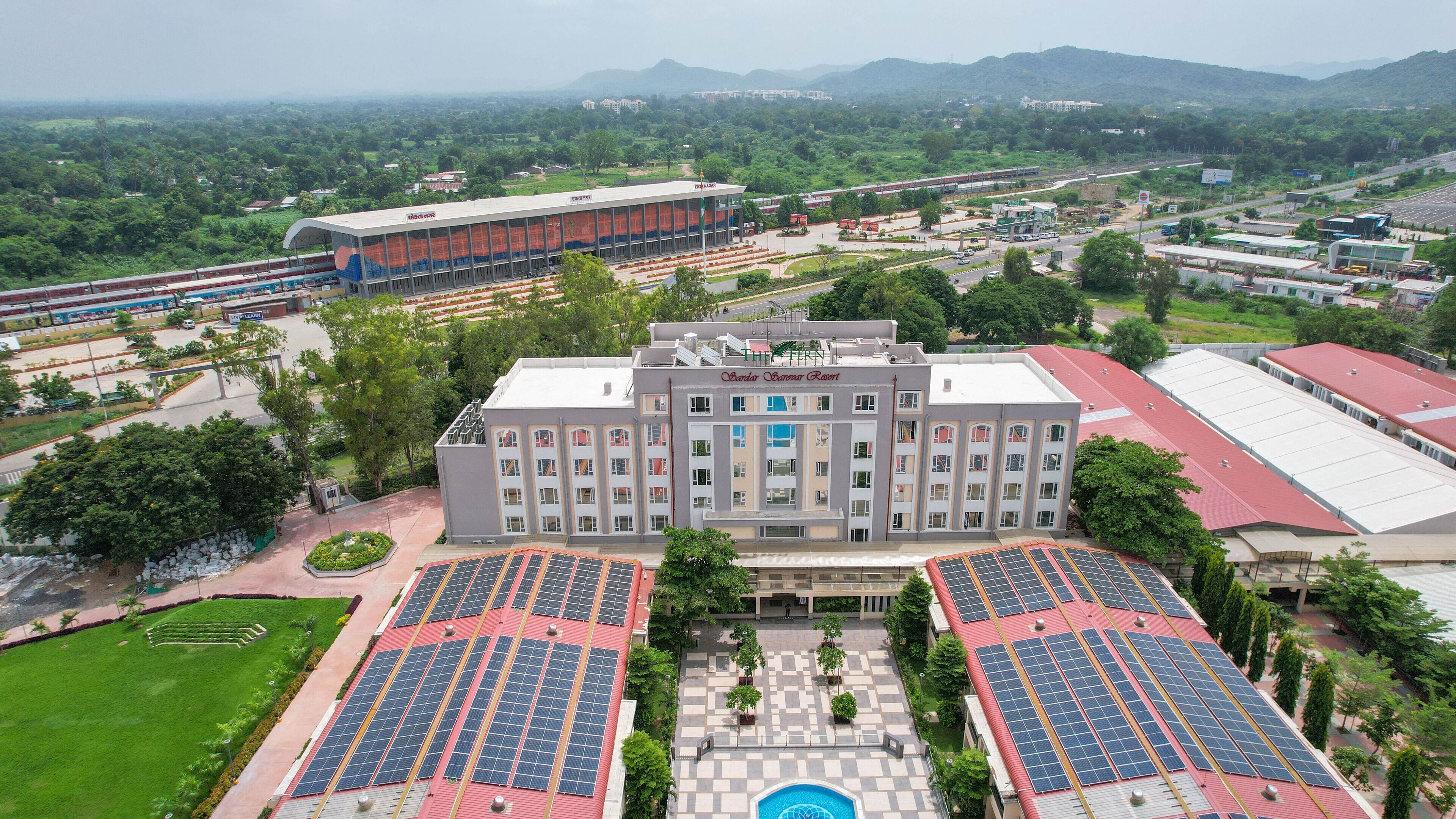 A large building with multiple floors, surrounded by green spaces and solar panels.