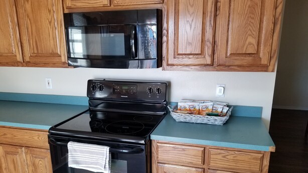 Una cocina con armarios de madera, estufa negra y microondas.