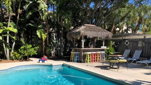 A swimming pool with lounge chairs and a thatched-roof structure. - SHORT WALK TO VILLAGE, BEACH - HEATED POOL - LUSH LANDSCAPING.
TWO UNITS. (Siesta Key)