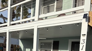 A two-story building with a porch, a door marked with the number 317, and outdoor seating with chairs and a table. - SHORT WALK TO VILLAGE, BEACH - HEATED POOL - LUSH LANDSCAPING.
TWO UNITS. (Siesta Key)